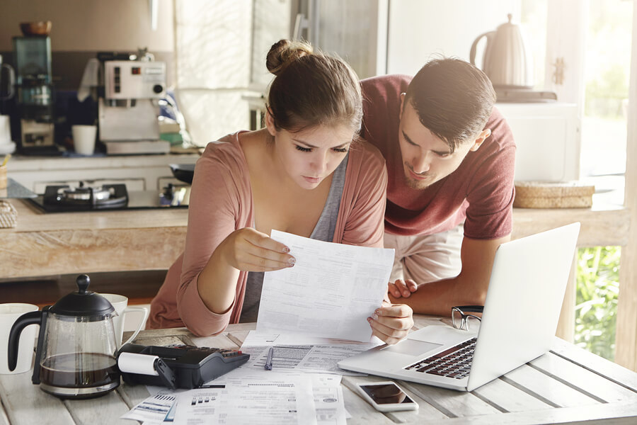 Scenic Young Family Doing Paperwork At Home. Wife Looking Worrie